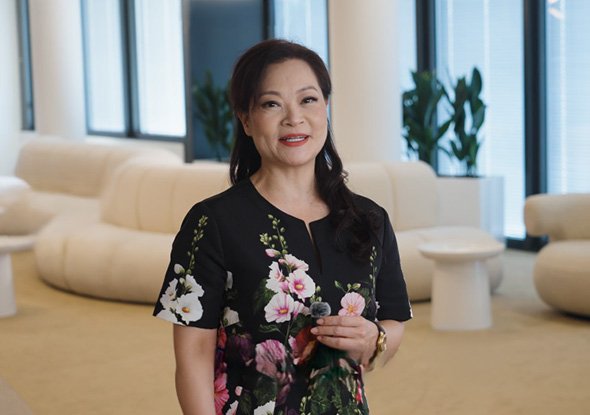 2026TravelRetail524242InterviewEva Yu holding a microphone in a floral dress in a lounge 1