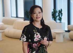 2026TravelRetail524242InterviewEva Yu holding a microphone in a floral dress in a lounge 1