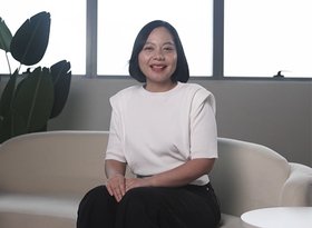 2026TravelRetail524245InterviewNadya Pamela seated on a sofa beside a black suitcase
