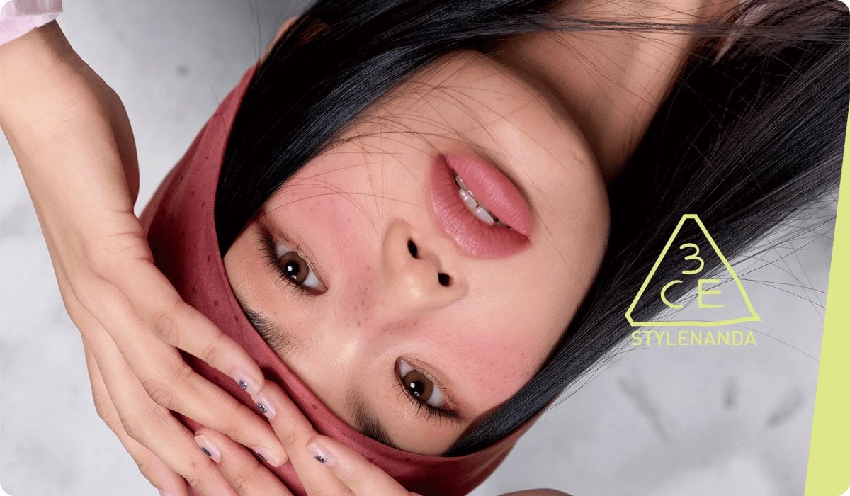 2025 consumer product division 3CE brand woman in red bandana with freckles and blush hands on head