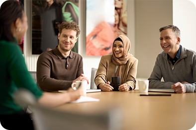 Zwei Männer und zwei Frauen sitzen gemeinsam am Tisch im Büro und unterhalten sich