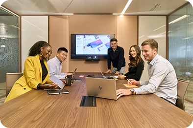 Eine Gruppe von Kolleginnen und Kollegen sitzt im Konferenzraum und arbeitet gemeinsam an einer Präsentation