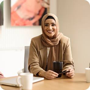 Eine Frau sitzt ihrer Kollegin gegenüber am Schreibtisch und lächelt