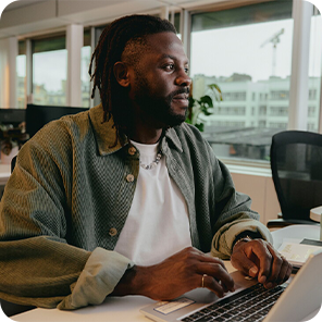 Ein Mann sitzt im Büro am Schreibtisch vor seinem Laptop und arbeitet