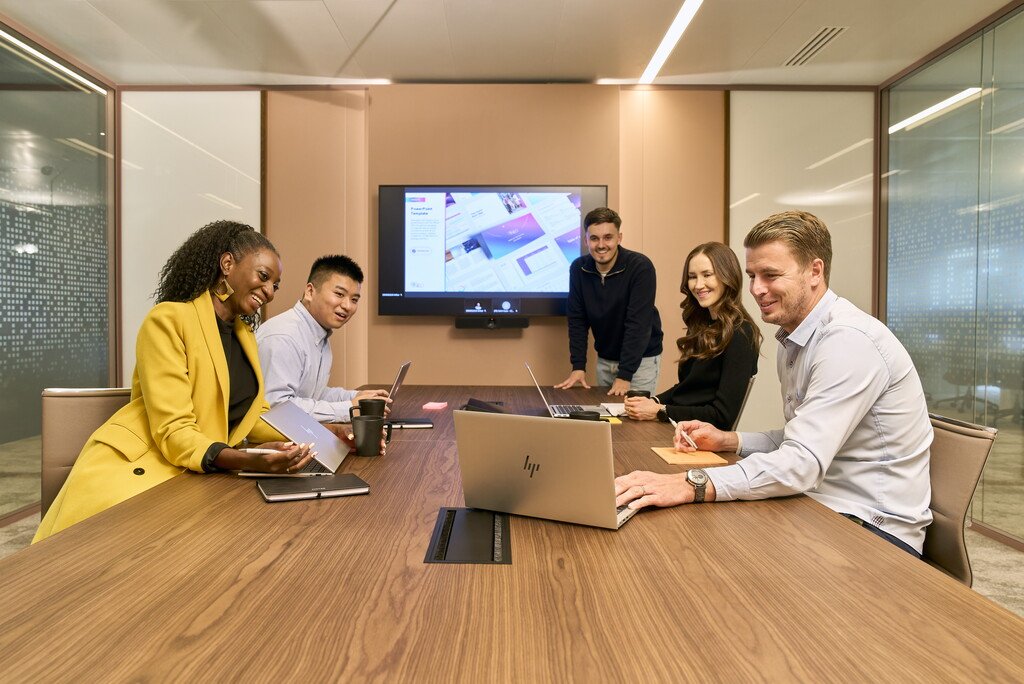 Eine Gruppe von Kolleginnen und Kollegen sitzt im Konferenzraum und arbeitet gemeinsam an einer Präsentation