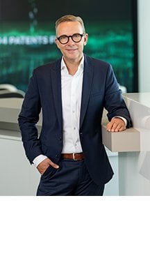 Neuer Chief Sustainability Officer Stefan Geister steht im Anzug an einen Tresen gelehnt