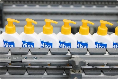 Mixa Flaschen mit gelben Deckel auf dem Fließband der Loreal Fabrik